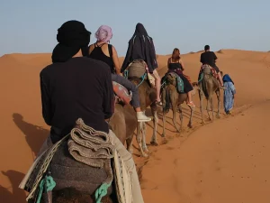 Riding camels into the dunes on the 4 days tour from Errachidia to Marrakech