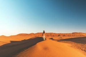 Walking alone on a dune crest at sunrise over the Sahara