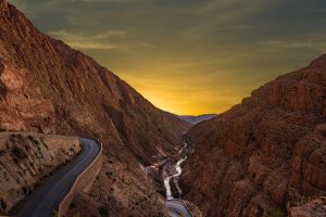 Road running through a red-walled gorge in southern Morocco at sunset