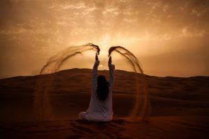Traveller with a scarf against the sunset over the Sahara dunes